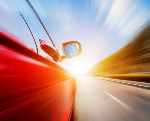 Car speeding down sunlit highway