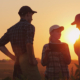 3 people talking in an open field at sunset