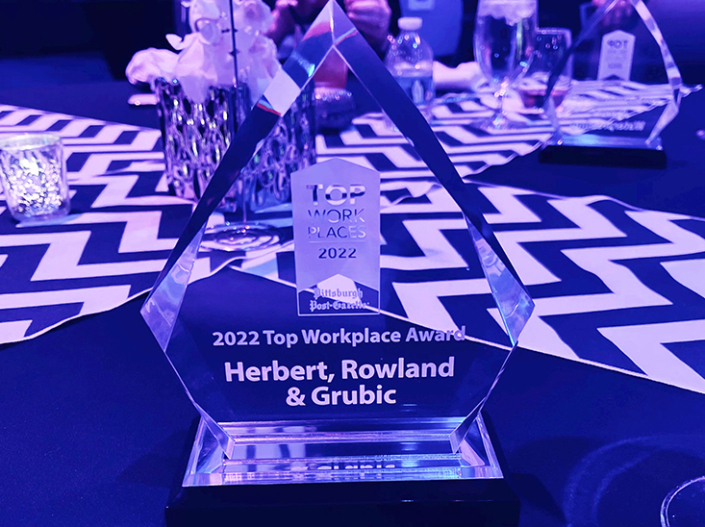 A crystal award for HRG as one of 2022's Top Work Places in Pittsburgh is bathed in purple light on a table at the ceremony