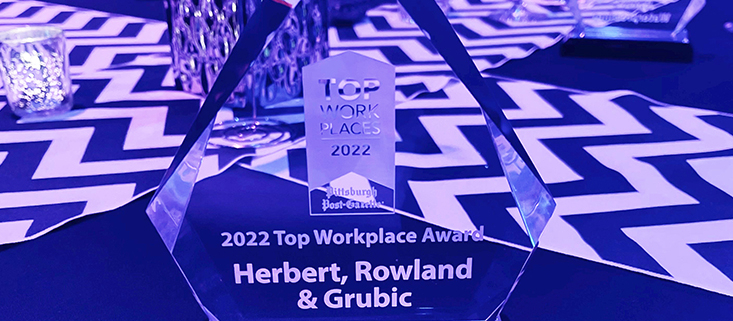 A crystal award for HRG as one of 2022's Top Work Places in Pittsburgh is bathed in purple light on a table at the ceremony