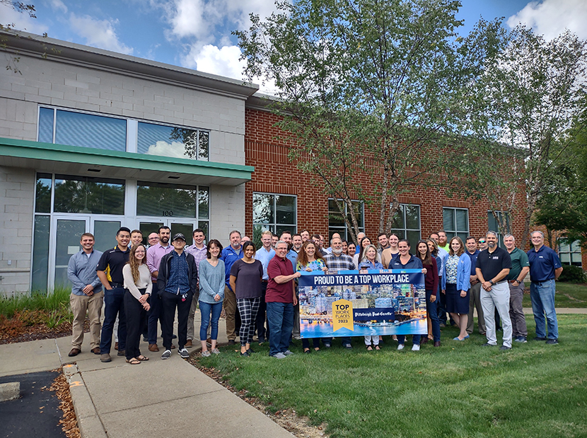 HRG's team holds a banner celebrating their inclusion on the 2023 list of Pittsburgh's Top Workplaces