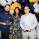 Clayton Whitlatch, Kara Smith, and Andrew Scampone accept HRG's awards at the Pittsburgh Top Workplaces ceremony, September 2024. They are standing in front of a wall of navy, yellow, and white balloons.