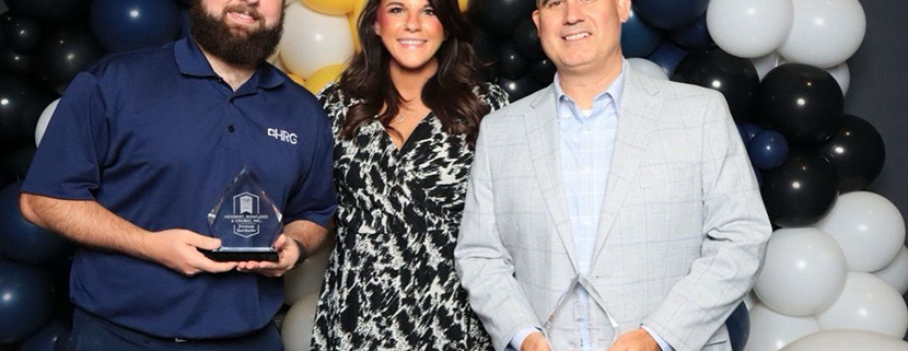 Clayton Whitlatch, Kara Smith, and Andrew Scampone accept HRG's awards at the Pittsburgh Top Workplaces ceremony, September 2024. They are standing in front of a wall of navy, yellow, and white balloons.