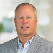 Dan Becker wearing a gray patterned suit coat and light blue patterned dress shirt.