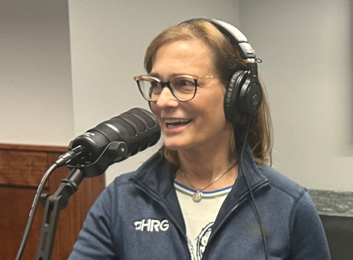 Melissa Rohland smiles and talks into a microphone as she records a podcast on smart water technology and digital twins