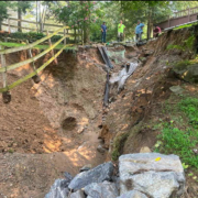 Township staff and their engineer examine a crater opened up by flash flood waterss