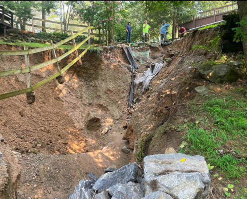 Township staff and their engineer examine a crater opened up by flash flood waterss