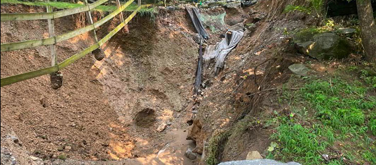 Township staff and their engineer examine a crater opened up by flash flood waterss